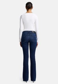 Jeans a zampa d'elefante di colore blu scuro, realizzati in denim, con vita alta, due tasche posteriori e un'etichetta del marchio discreta vicino all'orlo della vita.