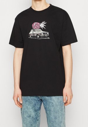 Black cotton t-shirt featuring a graphic of a vintage car with a pink pineapple on top. Short sleeves, relaxed fit, and crew neckline.