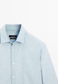 Camicia azzurro chiaro con colletto, maniche lunghe e etichetta del marchio "Massimo Dutti" all'interno del colletto.