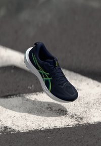 Navy running shoe featuring a mesh upper, green accents, textured surface, and a white midsole with the label "FF BOOST."