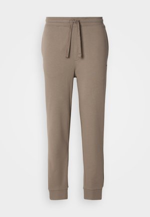Beige sweatpants in cotton blend with an elastic waistband and adjustable drawstring. Cuffs are ribbed, featuring a smooth texture.