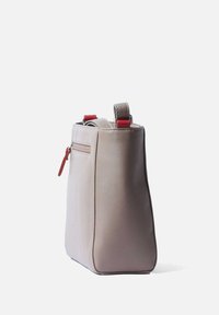Leren tas in lichtgrijs met een gestructureerde vorm, voorzien van rode accenten op de straps en een kleine ritsvak aan de zijkant.