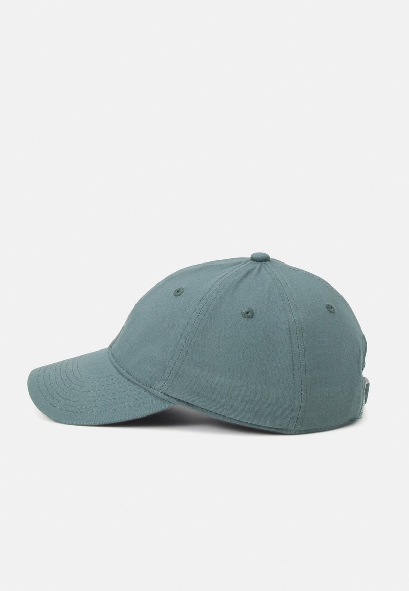 Casquette de baseball bleu clair à six panneaux avec des œillets cousus et une visière incurvée, vue de côté sur un fond uni.