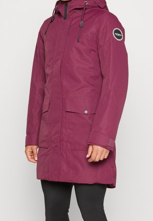 Fioletowy, zimowy płaszcz o średniej długości z kapturem, przednimi kieszeniami, zamkiem błyskawicznym i zatrzaskami, noszony na czarnych legginsach.