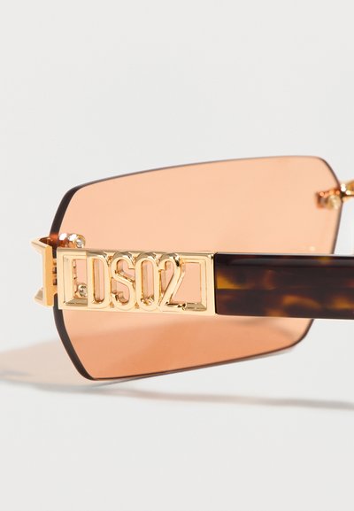 Γυαλιά ηλίου με ορθογώνιους φακούς με κεχριμπαρένια απόχρωση, σκουρόχρωμους βραχίονες σε μοτίβο χελωνόκαρπου και χρυσές λεπτομέρειες με το λογότυπο DSQ2 στα πλευρά.