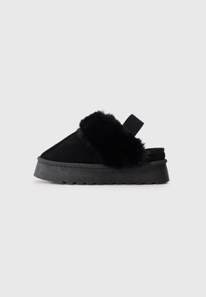 Sorte slip-on loafers med en blød faux fur-overdel, polstret sål og elastisk strop bagpå for nem påtagning. Flad, tekstureret ydersål.