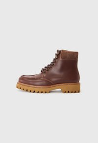 Botas tobilleras de cuero marrón con acentos de ante, puntera redonda y suela de goma texturizada. Presenta ojales de metal y cordones planos.