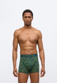 Πράσινα μπόξερ με σχέδια, κατασκευασμένα από μαλακό ύφασμα, με μπλε ελαστική μέση που φέρει το λογότυπο "BJÖRN BORG" και σχέδια φύλλων.