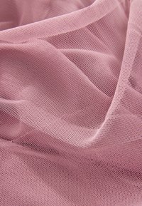 Tessuto di tulle rosa chiaro, con una texture a rete fine, che presenta morbide pieghe fluenti e un aspetto leggermente trasparente.