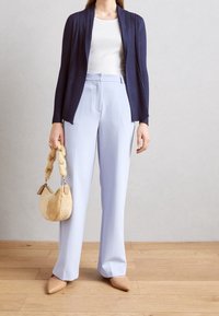 Námořnický žebrovaný otevřený kardigan přes bílý top, doplněný světle modrými kalhotami s širokými nohavicemi. Celý vzhled dotvářejí béžové špičaté baleríny a tmavě béžová nadýchaná kabelka.