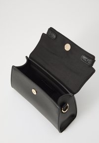 Sort læderhåndtaske med en glat overflade, guldlåse, magnetisk lukning og et åbent rum, der viser indre design.