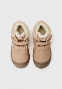 Une paire de bottes beiges pour tout-petits avec des bandes velcro et une doublure en polaire douce, vues de dessus sur un fond blanc.