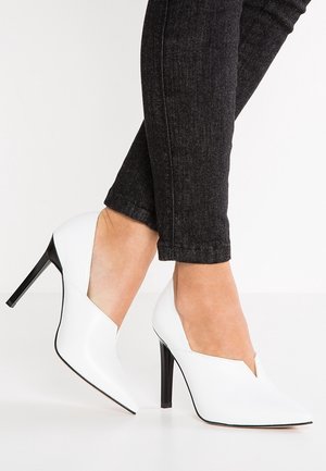 White high-heeled shoes with a pointed toe and a V-cut design; smooth leather material and a glossy black stiletto heel.