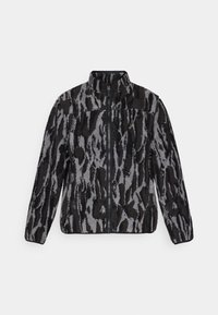 Veste en polaire avec un col haut, présentant un imprimé animal abstrait gris et noir, fermeture éclair et tissu texturé.