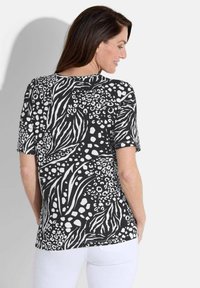 T-shirt met korte mouwen in zwart-wit, featuring een abstract dierenprint met luipaard- en zebra-patronen. Zachte stof, iets gebogen zoom.