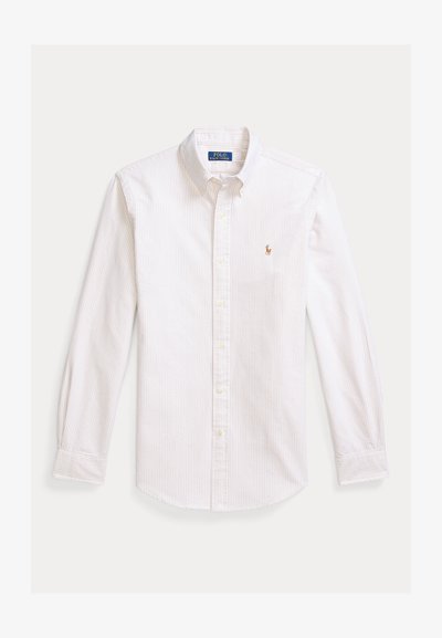 Hvit skjorte med knapper og lyseblå og beige vertikale striper. Har spiss krage, lange ermer og en liten brodert logo på brystet.