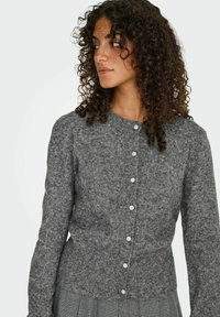 Cardigan en tricot gris avec un col rond et des manches longues, doté de boutons et d'un tissu texturé. Design ajusté.