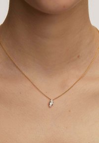 Collar de cadena de oro con un colgante en forma de marquesa adornado con pequeñas piedras preciosas transparentes. La cadena presenta un diseño de eslabones delicados.