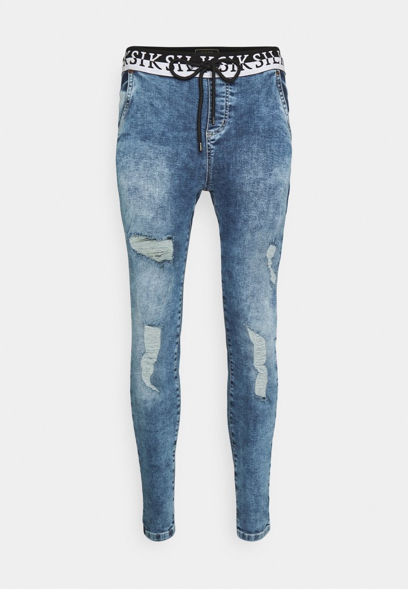 Bleka blå denim-joggers med slitningar på låren, svart midjesnörning med vit branding, avsmalnande passform och standard benöppningar.