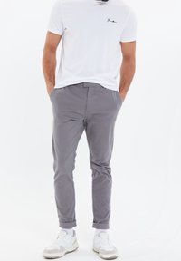 Gray cotton-chino pants with a slim fit, featuring rolled cuffs. Paired with a plain white t-shirt and white sneakers with gray accents.
