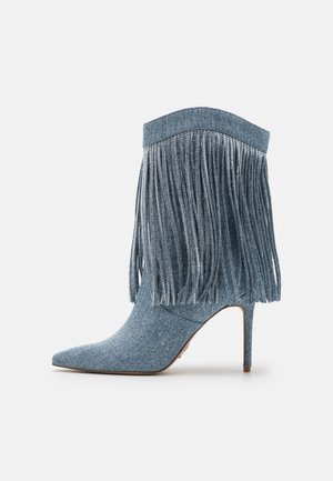 Niebieskie botki z denimu z frędzlami, szpiczastym noskiem i obcasem szpilką. Gładka faktura i kontrastujący materiał na górze.