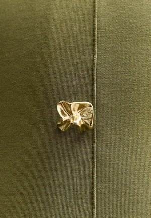 Tessuto verde oliva con una texture liscia presenta un accento a forma di fiocco dorato metallico attaccato al bordo. I dettagli di cucitura sono visibili.