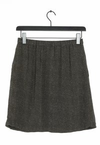 Jupe noire à pois blancs, taille élastique, design plissé, suspendue à un cintre noir sur fond blanc.