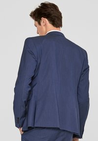 Dunkelblaues Sakko mit einem schlanken Design, das einen einzelnen Schlitz hinten und einen strukturierten Stoff aufweist. Vier Knöpfe an den Manschetten.