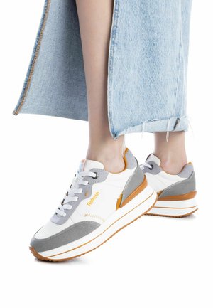 Sneakers bianchi e grigi con accenti arancioni, caratterizzati da un design in tessuto testurizzato, chiusura con lacci e suola imbottita. Orlo in denim sfrangiato visibile.