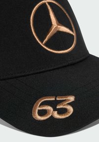 Čierna čiapka s zlatou výšivkou loga Mercedes a číslom 63, s hladkou textúrou tkaniny a zakriveným krempou.