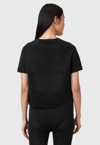 Zwarte crop top met een getextureerd, geribbeld patroon, ronde halslijn en korte mouwen; gecombineerd met bijpassende geribbelde broek.