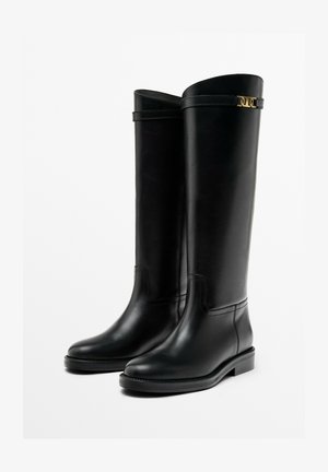 Bottes noires en cuir montantes avec une finition lisse, bout rond, petit talon carré et accents subtils en métal doré sur la tige.