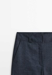 Pantalon bleu foncé sur mesure avec passants de ceinture, poches latérales et braguette zippée sur fond blanc.