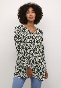 Blusa a maniche lunghe con scollatura a V nera, con motivi floreali e foglie bianchi; tessuto leggero con vestibilità rilassata.