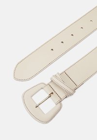Beiger Leder Gürtel mit quadratischer Schnalle und goldfarbener Hardware, sichtbaren Stichen und mehreren Einstelllöchern.
