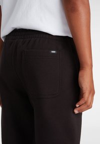 Zwarte joggingsbroek met een elastische tailleband, voorzien van een achterzak en een klein Vans logo label. Soepele textuur met een slim fit.