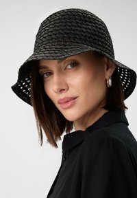 Black woven bucket hat with a wide brim, featuring a textured pattern and open weave. Details include light gray accents and a soft finish.