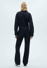 Jeans de mezclilla oscura con un diseño de pierna recta, que cuentan con bolsillos traseros y una cintura alta. La tela tiene una textura suave y detalles de costura mínimos.