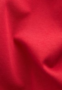 Red cotton fabric with a smooth texture, featuring subtle folds and a plain finish. No patterns or accents are visible.