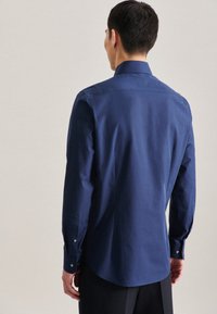 Marineblauwe langemouwen shirt van gladde stof, met een klassieke kraag en knoopmanchetten, met een gebogen zoom aan de achterkant.