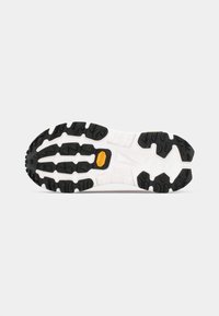 Semelle de chaussure de sport en noir et blanc avec des motifs de profondeur et un logo Vibram jaune au centre sur fond blanc.