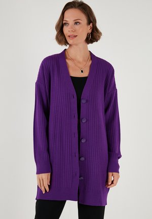 Purple ribbed cardigan with a V-neck, long sleeves, and five textured buttons down the front. Material appears soft with a smooth finish.