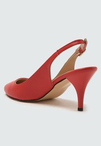 Chaussure à talon aiguille rouge en cuir avec bout pointu, sangle à boucle et talon fin, présentée en vue de profil.
