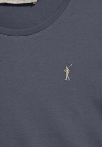 Marinblå bomullströja med rund halsringning, med en liten, ljus broderad golfa design på bröstet.