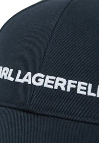 Navy-blaues Cap aus strukturiertem Stoff mit weißem, gesticktem "KARL LAGERFELD"-Logo auf der Vorderseite. Gebogener Schirm, strukturierte Form.