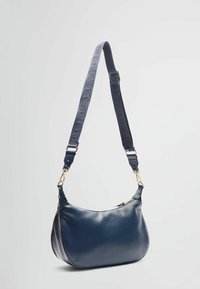 Granatowa skórzana torba na ramię o zaokrąglonym kształcie, złotych okuciach, zamknięciu na suwak oraz teksturowanym pasku z tkaniny z wzorem logo.