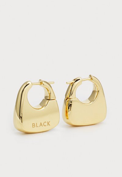 Pendientes de aro de metal de tono dorado con un acabado liso y pulido, y una forma única y gruesa. Grabados con la palabra "BLACK."