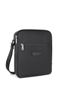 Borsa a tracolla nera in tessuto con chiusura zip, tasca frontale e tracolla testurizzata. Presenta un patch con logo e dettagli in hardware argentato.