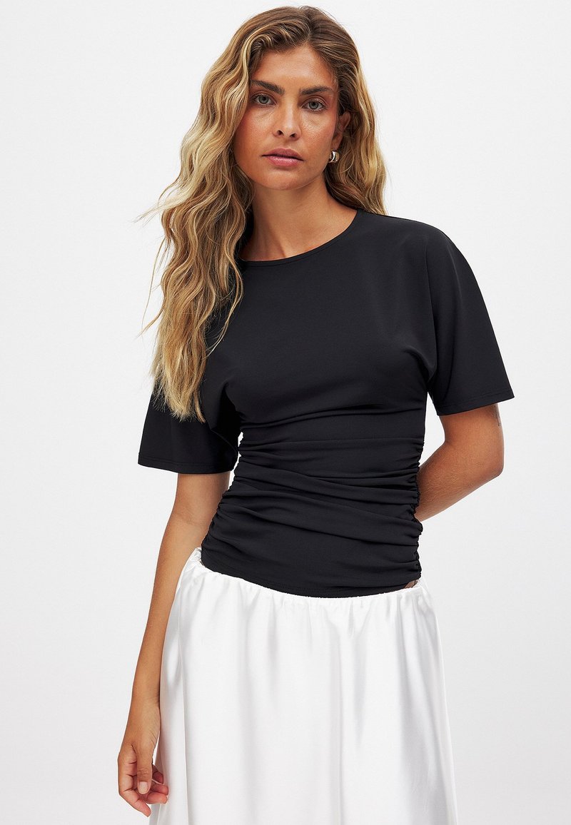 Juodas trumpas rankovėmis viršus, pagamintas iš glotnaus audinio, su apvaliu iškirpimu ir raukšlių detale liemenyje, suteikiančia prigludusią siluetą.