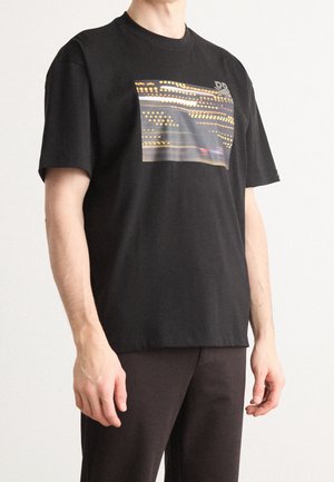 Czarny t-shirt z bawełny, z prostokątną grafiką w żółte i białe linie, okrągłym dekoltem i krótkimi rękawami.